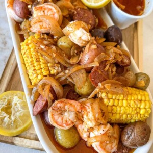 shrimp corn sausage and potatoes on a platter with garlic butter sauce on it