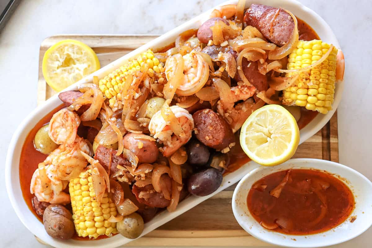 shrimp corn sausage and potatoes on a platter with butter sauce on it