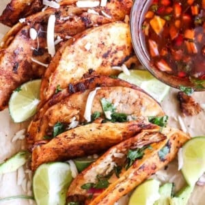 chicken birria quesatacos on a board with lime wedges and consome