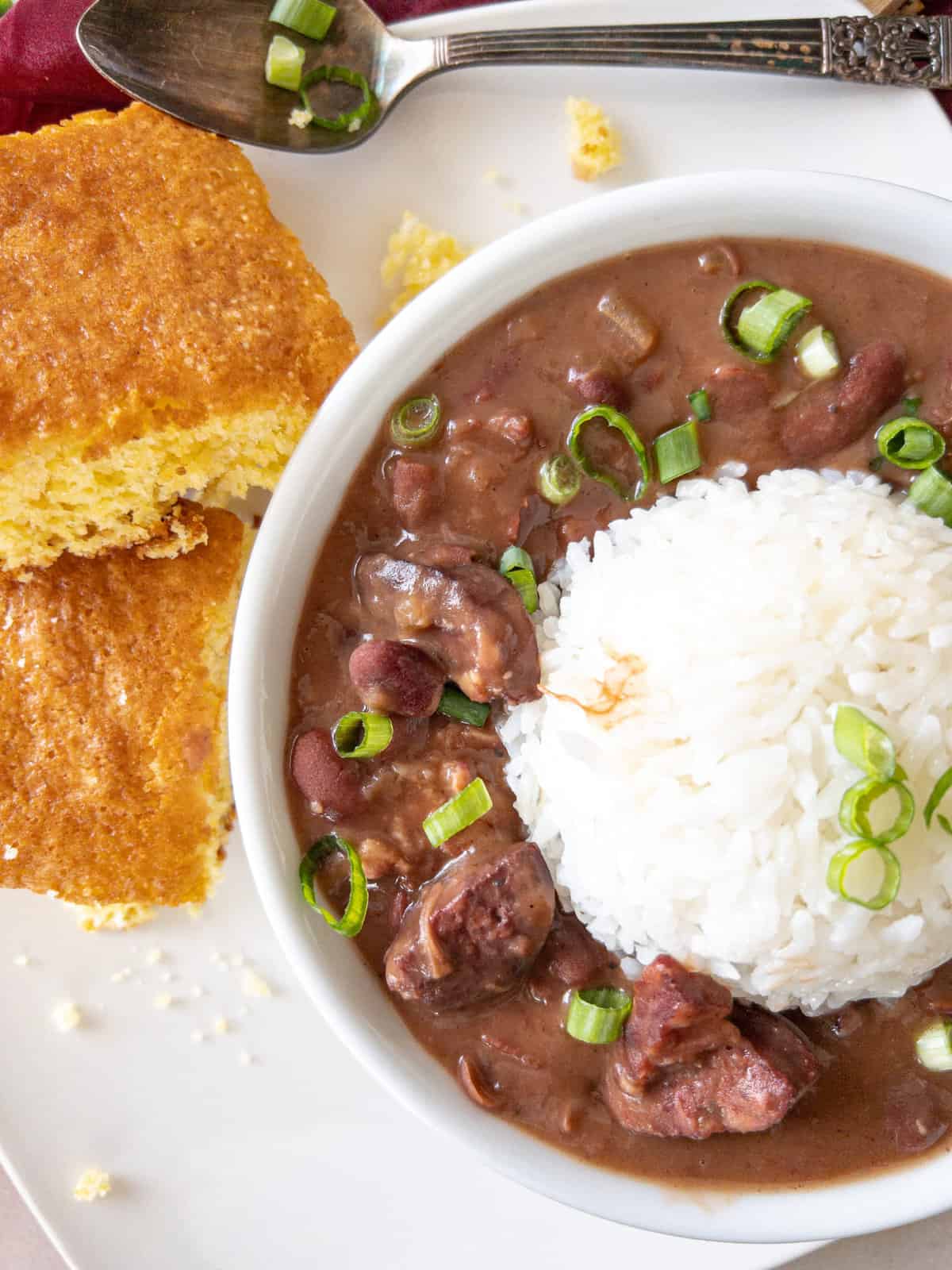 a bowl of red beans and rice with a side of honey butter cornbread