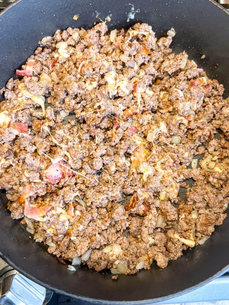 cooked ground beef in a skillet with cheese and bacon