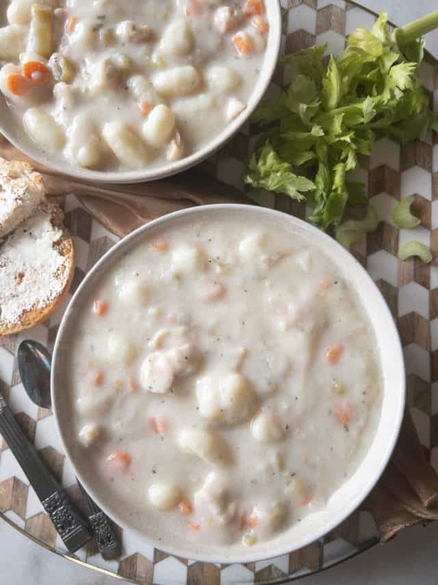chicken and gnocchi soup in a bowl with a piece of buttered bread nearby