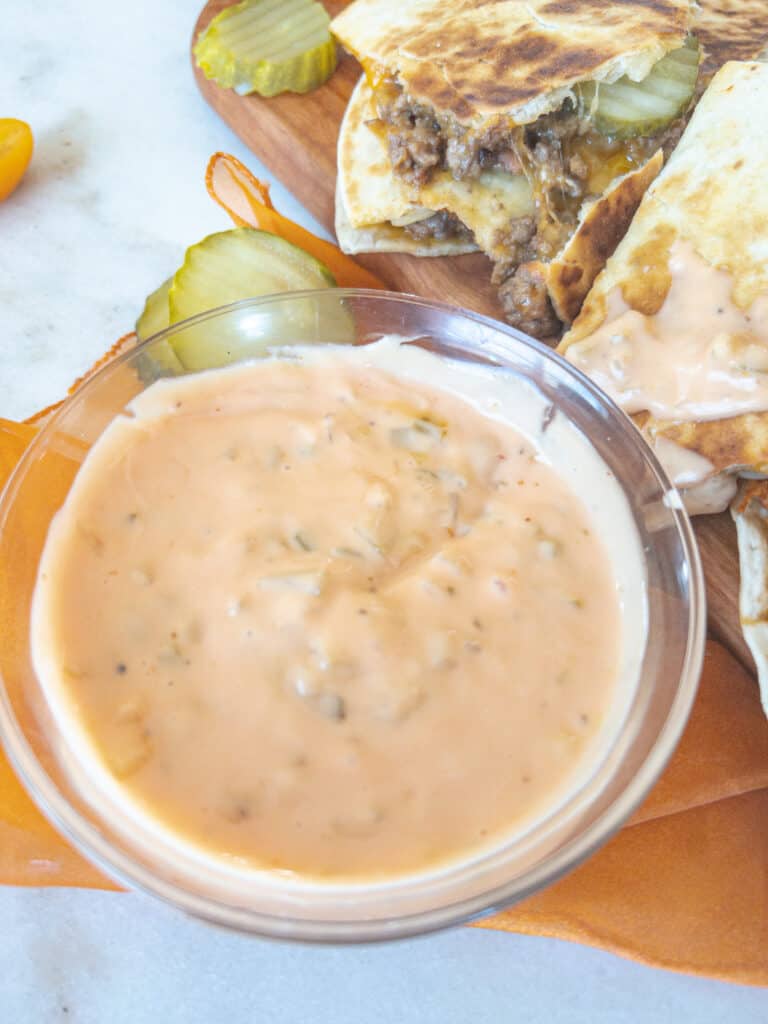 a bowl of in and out sauce next to slices of a burger quesadilla