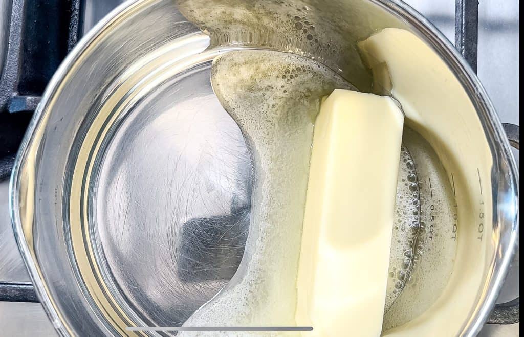 melting butter in a sauce pan to make the peach cobbler topping for French toast