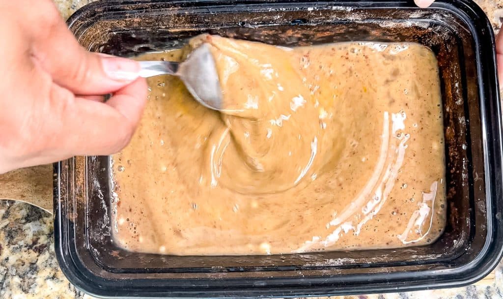 a custard being mixed in a bowl to coat the peach cobbler stuffed French toast