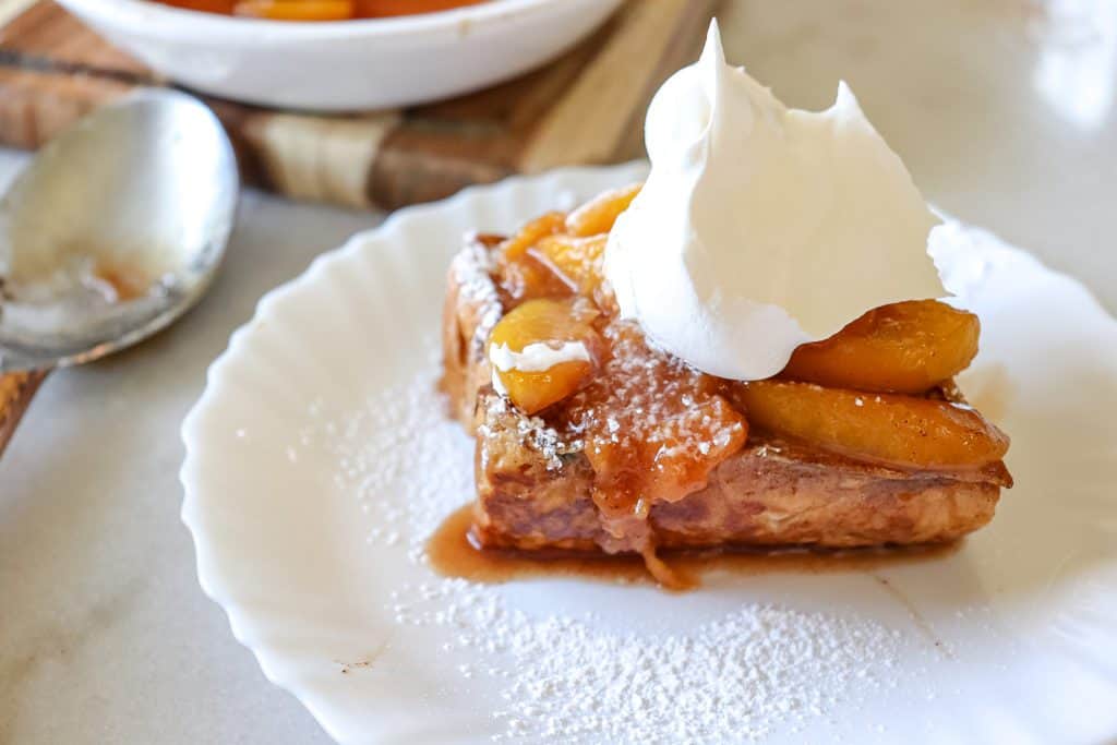 peach cobbler stuffed French toast on a plate with a dollop of whipped cream on  
