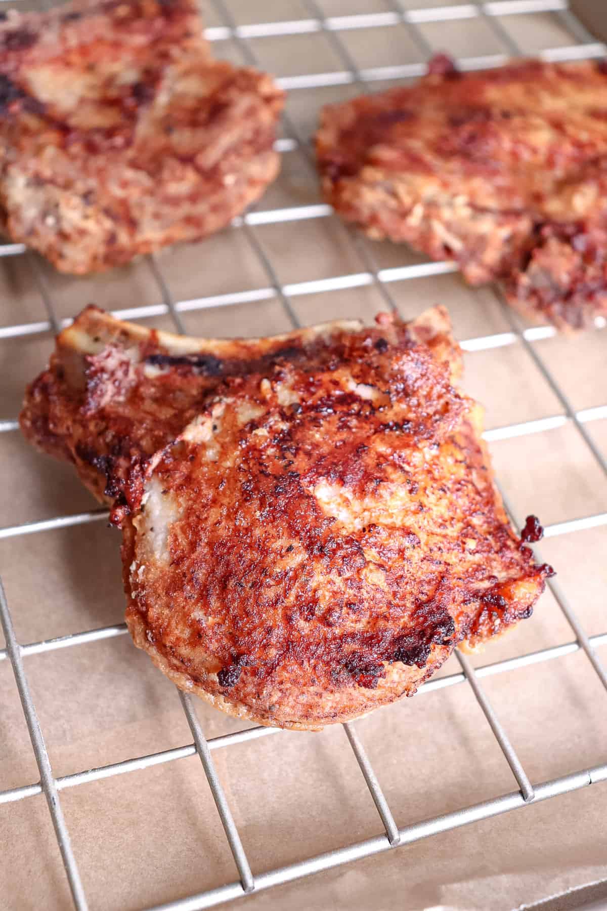 pork chops that have been fried sitting on a cooling rack