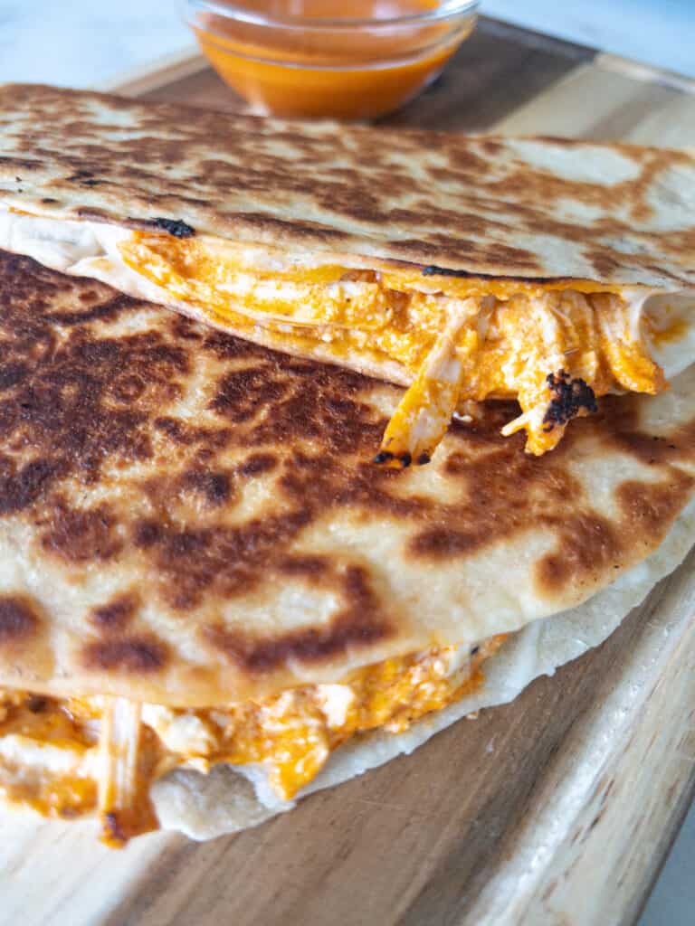 A close up view of a quesadilla cut in half to reveal the saucy, cheesy center.