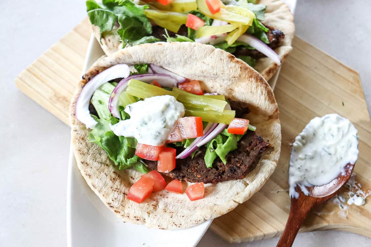 gyro sandwiches with gyro meat, tzatziki sauce, tomatoes, pickles, and lettuce in a pita bread
