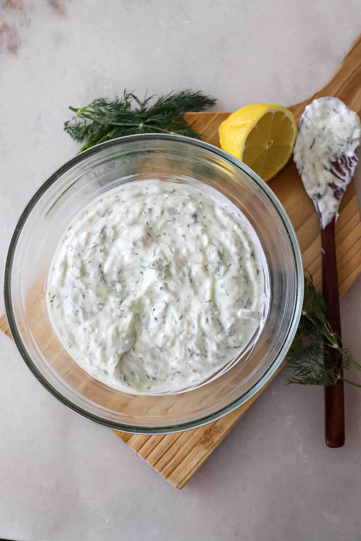 tzatziki sauce in a bowl with a lemon wedge and spoon on the side