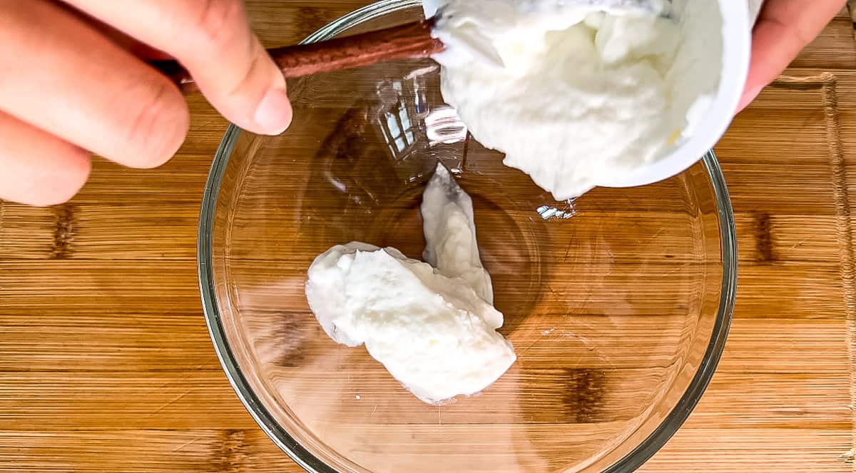 adding Greek yogurt to a bowl for tzatziki sauce