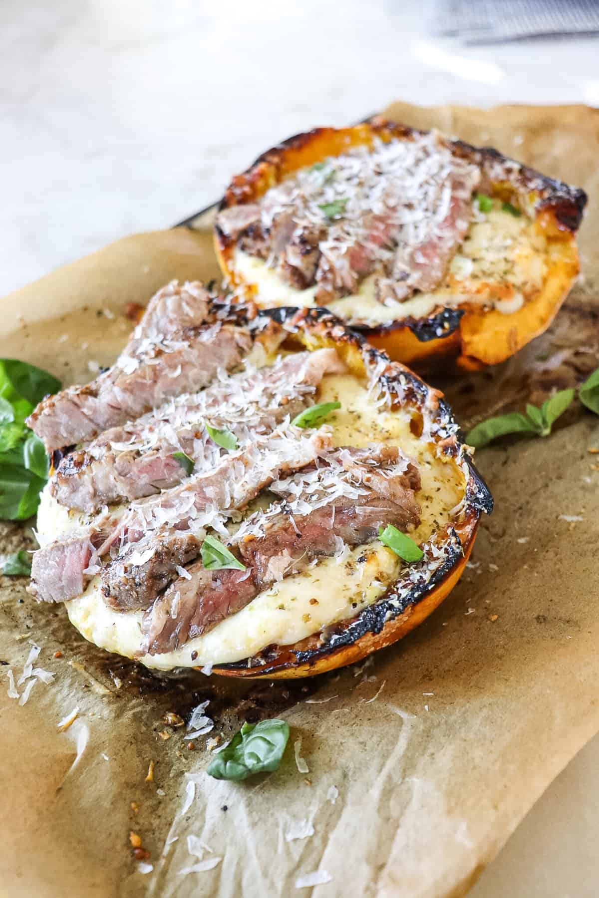 Two baked squashes filled with alfredo and topped with steak