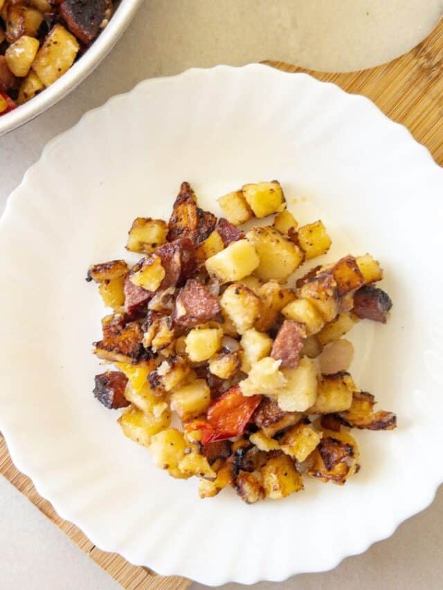 skillet potatoes and smoked sausage on a small white plate