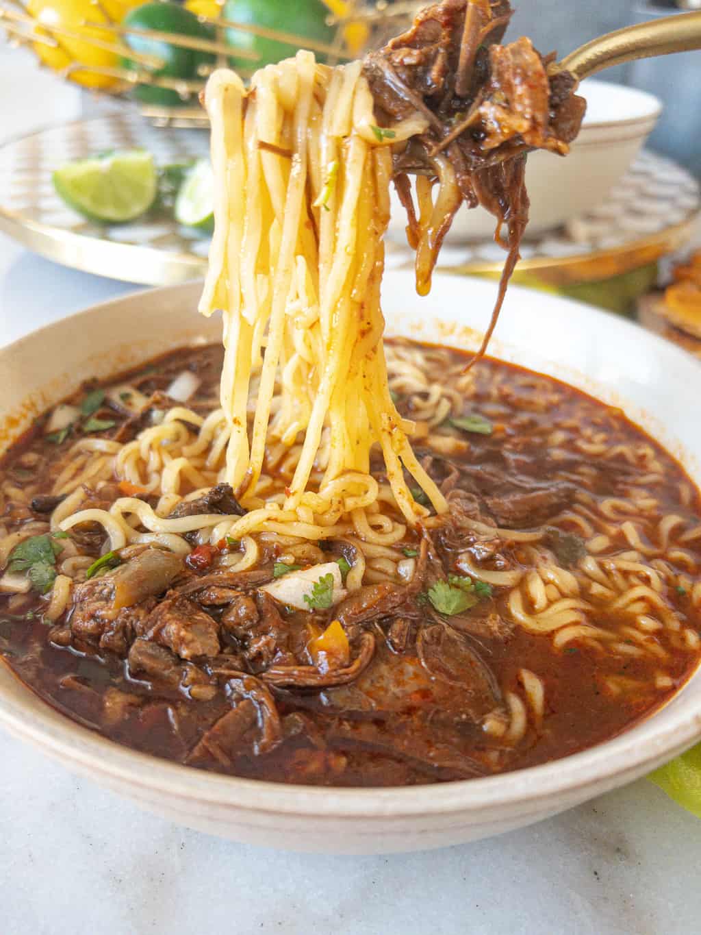 fork full of birria ramen with beef showing a "noodle pull."