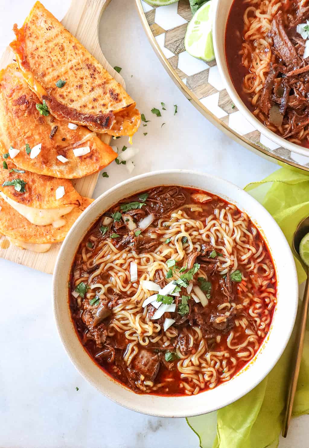 birria ramen in a bowl with four cheese quesadillas next to it