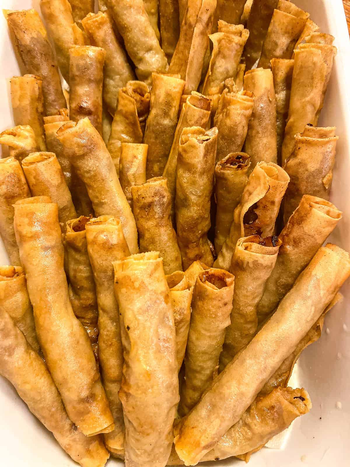 a lot of fried lumpia piled in a bowl, ready to be served
