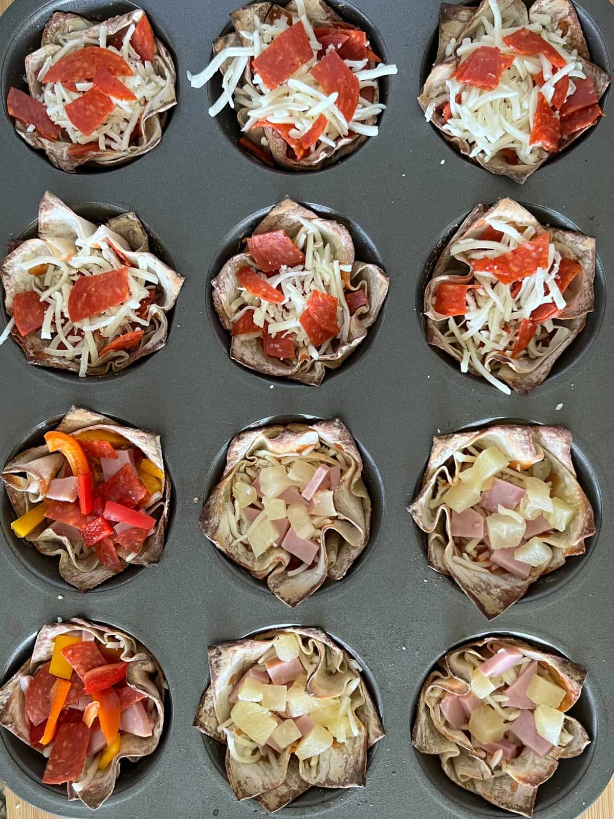 assembling mini pizza cups with cheese and pepperoni in a cupcake pan