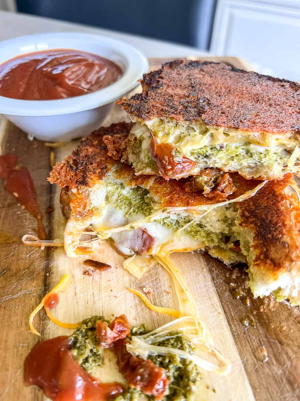 pesto grilled cheese cut in half on a cutting board