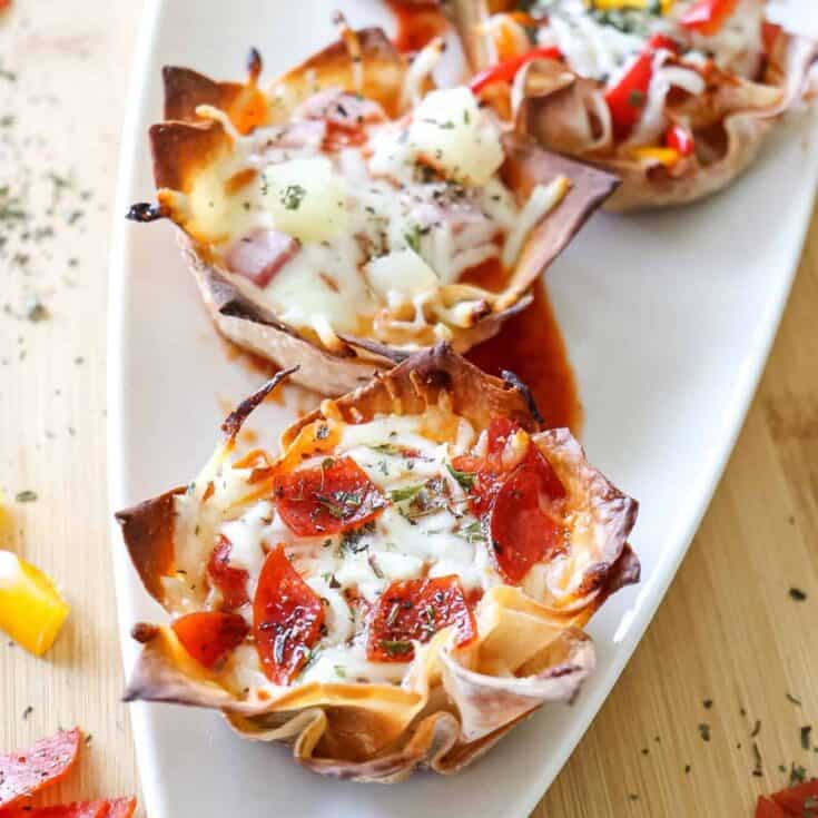 mini pizza cups made with wonton wrappers sitting on a white platter