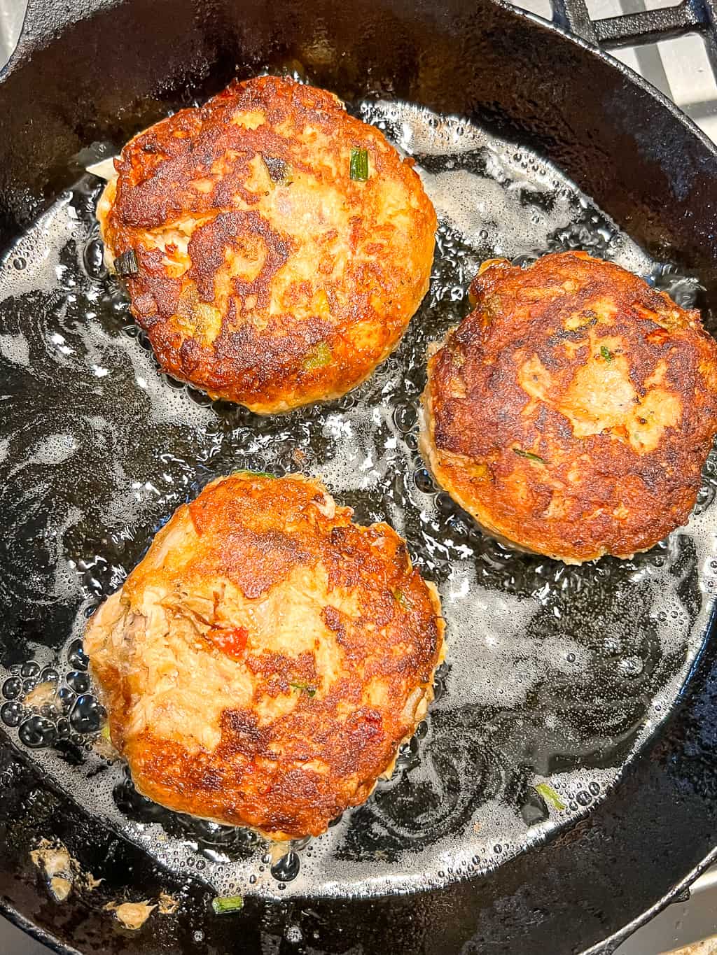 frying salmon croquettes in a cast iron skillet