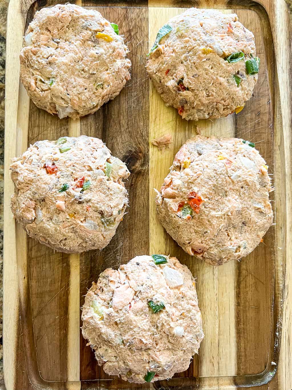 salmon croquette patties that are uncooked sitting on a cutting board