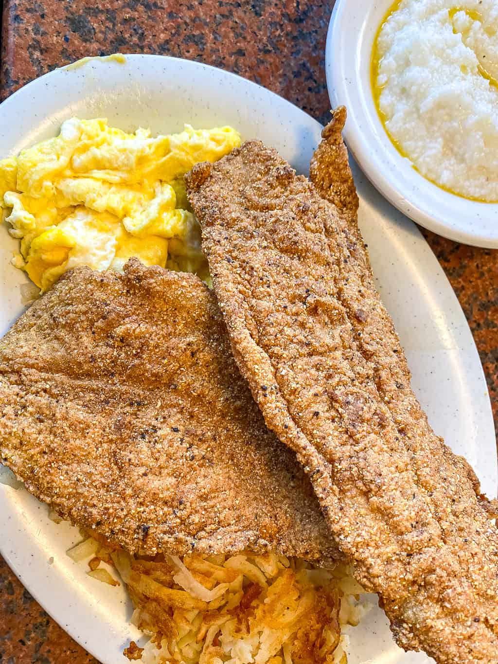 southern fried catfish on a plate with eggs and a side of grits
