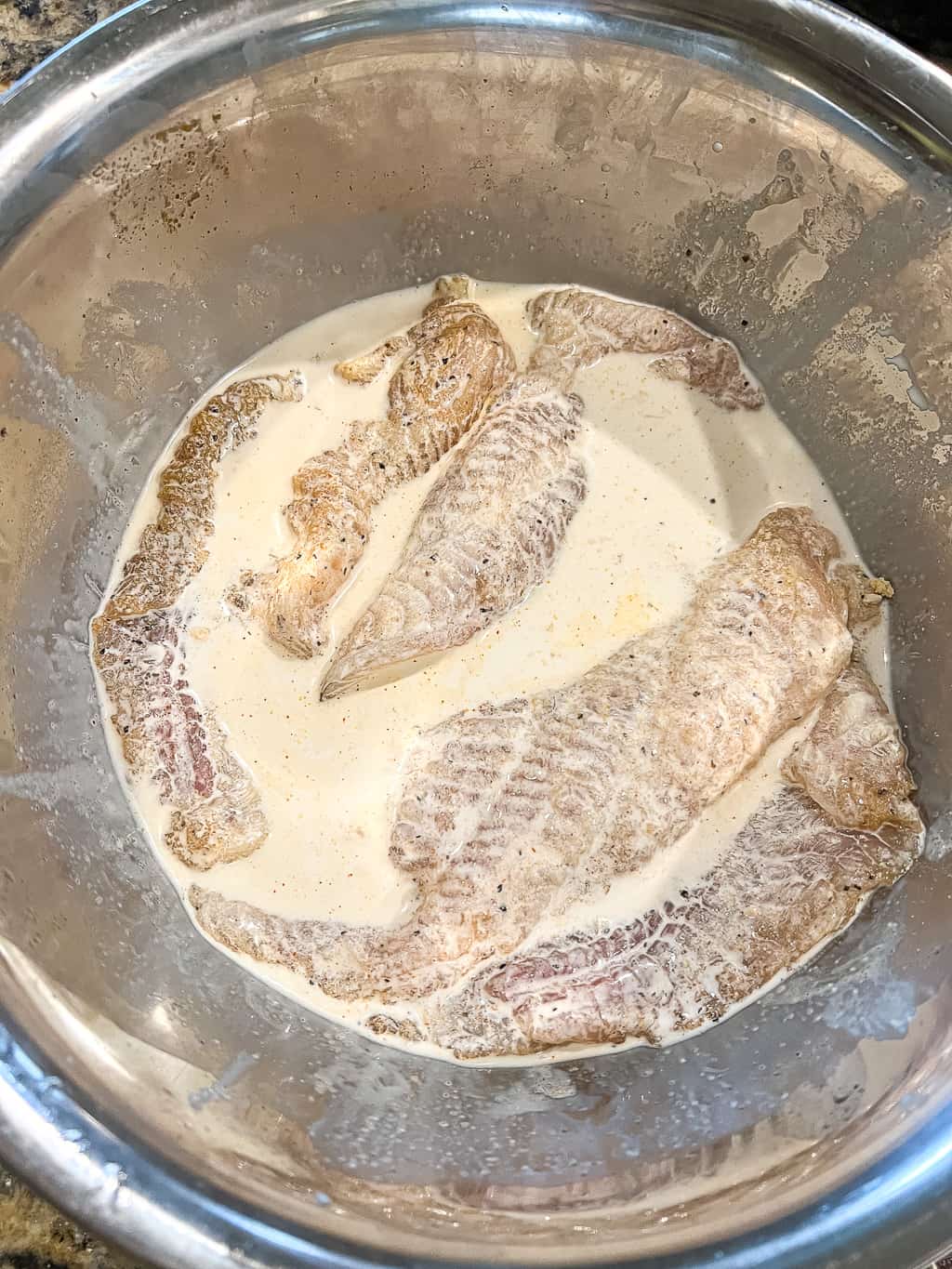 catfish fillets soaking in buttermilk before breading