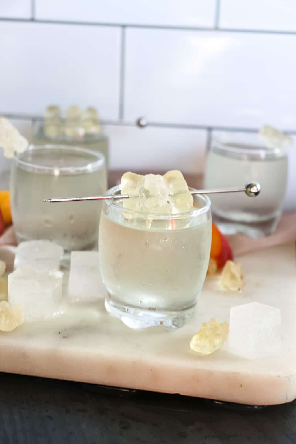 white gummy bear shot poured into a shot glass with white gummy bears on a stir stick for garnishment