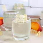 white gummy bear shot poured into a shot glass with white gummy bears on a stir stick for garnishment