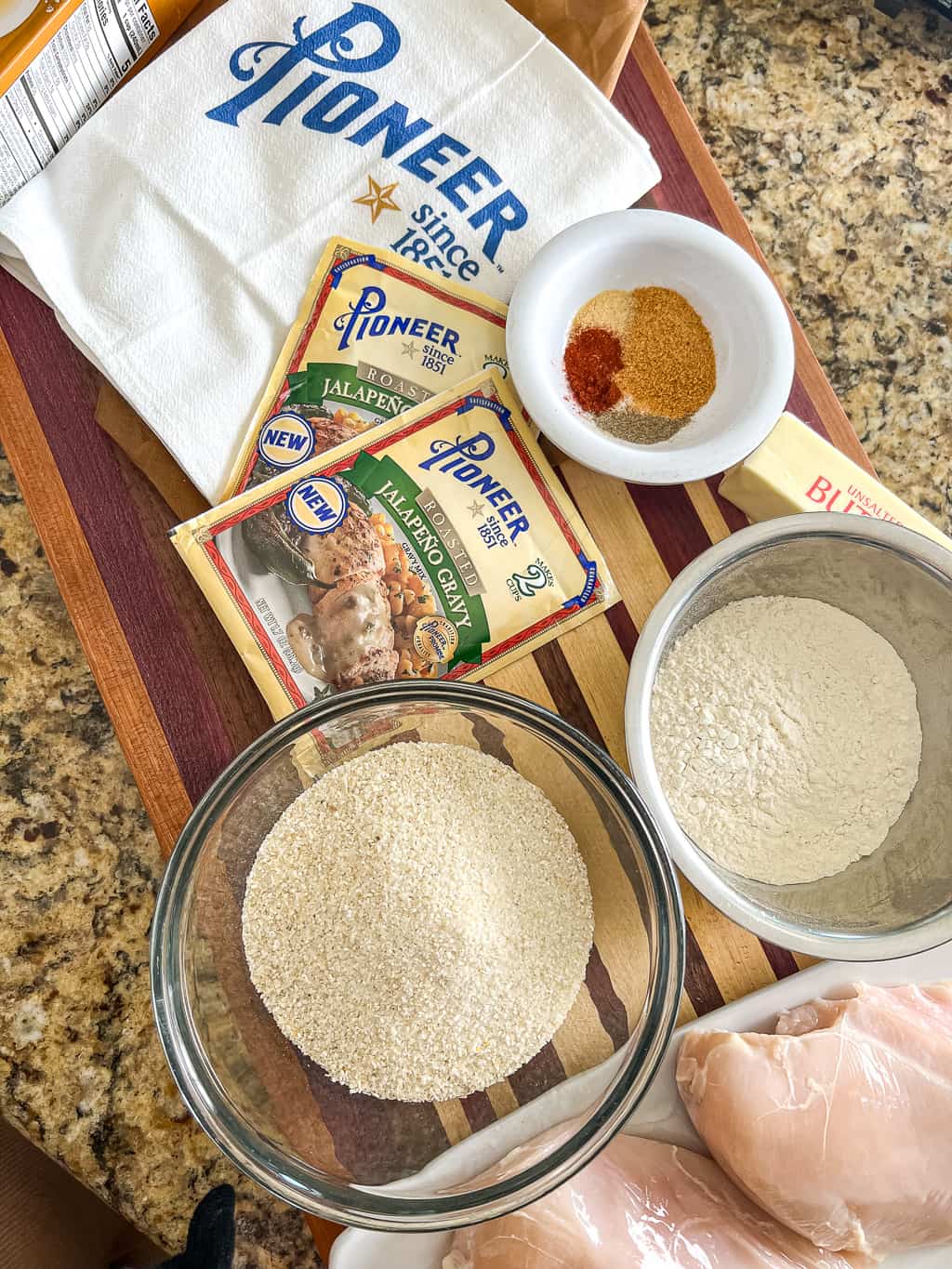 bowl of dry grits, flour, seasoning, and packet of Pioneer gravy that are ingredients for chicken with grits recipe