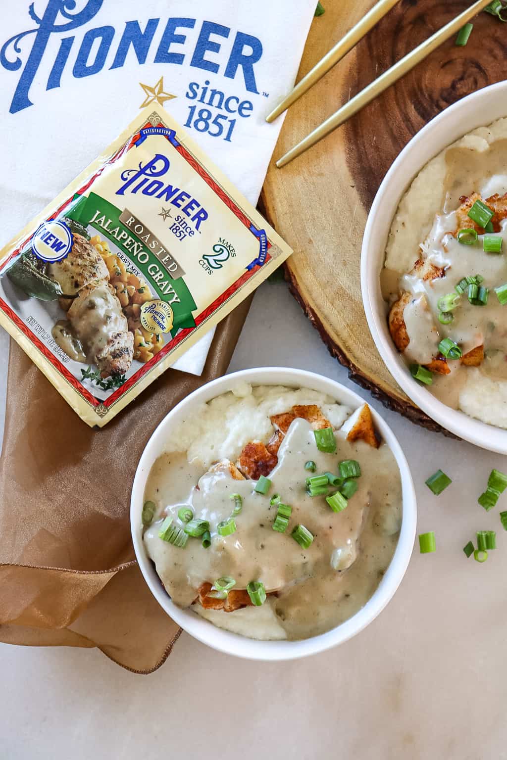 smothered chicken over grits in a bowl with green onions sprinkled on top