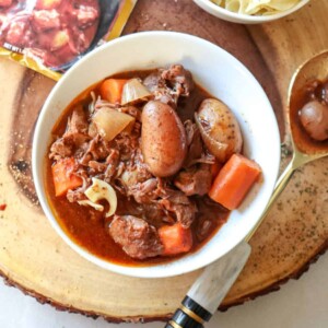 beef stew in a bowl with potatoes and carrots with a serving spoon alongside the bowl