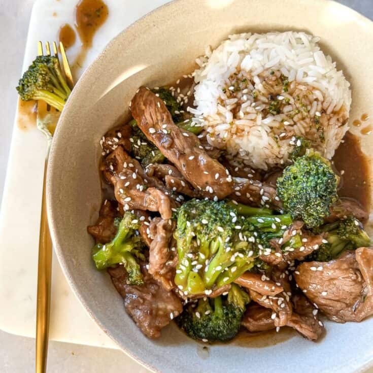 beef and broccoli in a white bowl with a side of jasmine rice