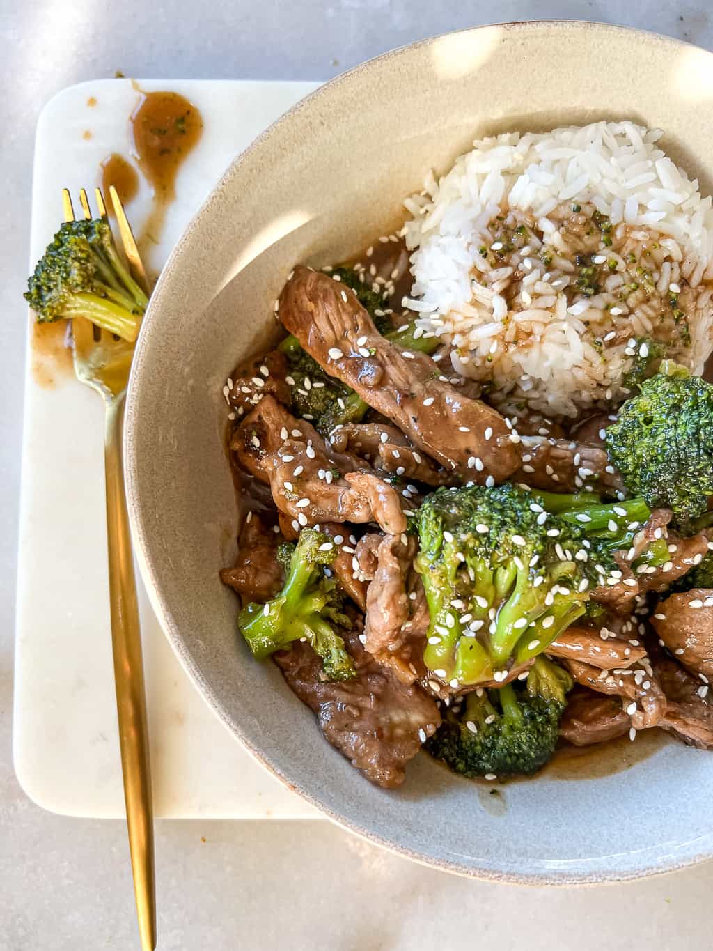 beef and broccoli in a bowl with a side of white rice