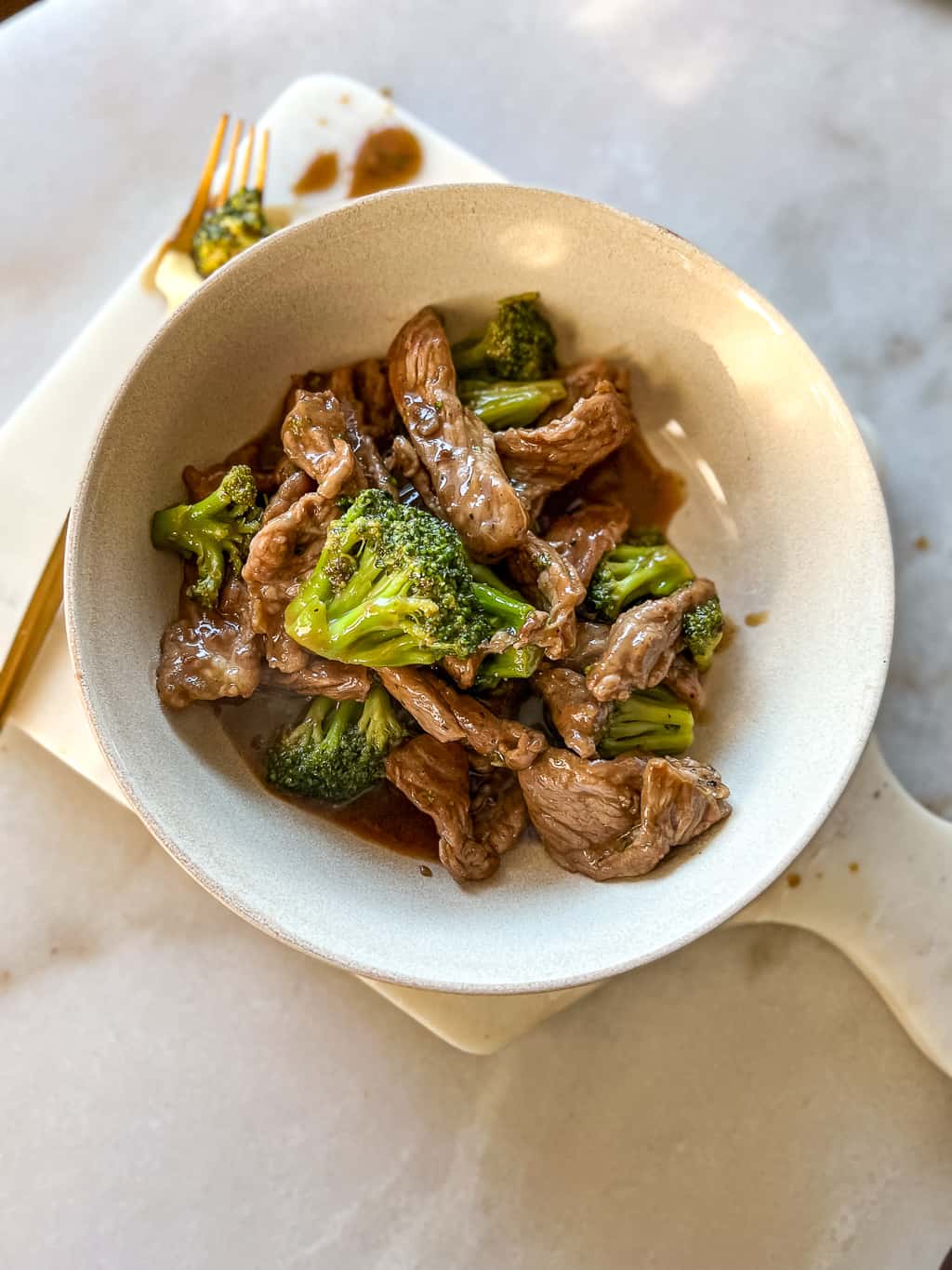 beef and broccoli in a white bowl on the table