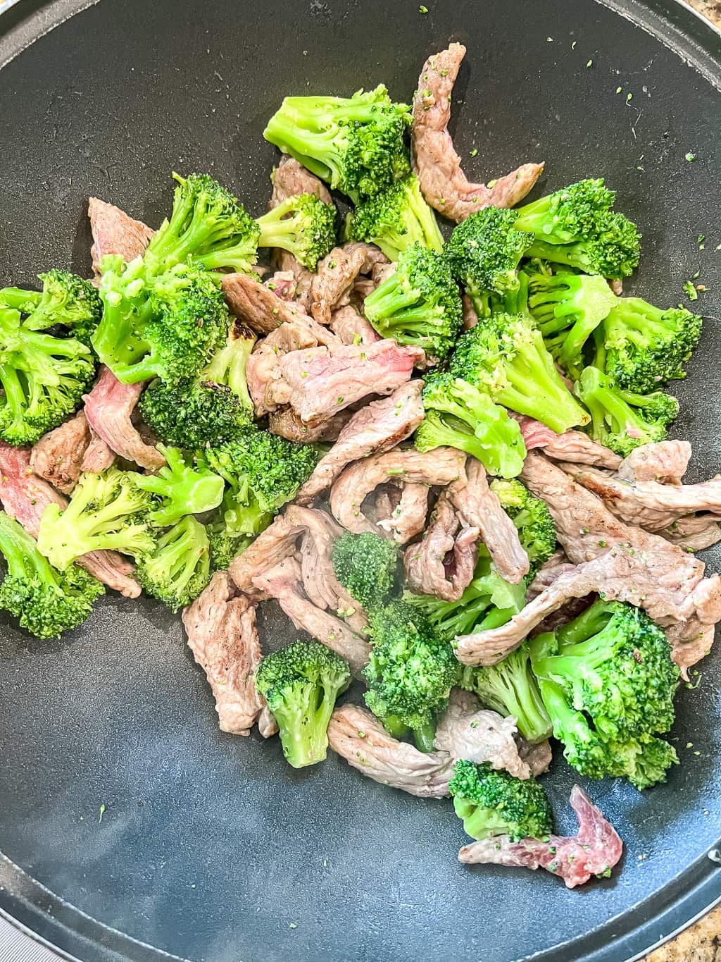 beef and broccoli cooking in a wok