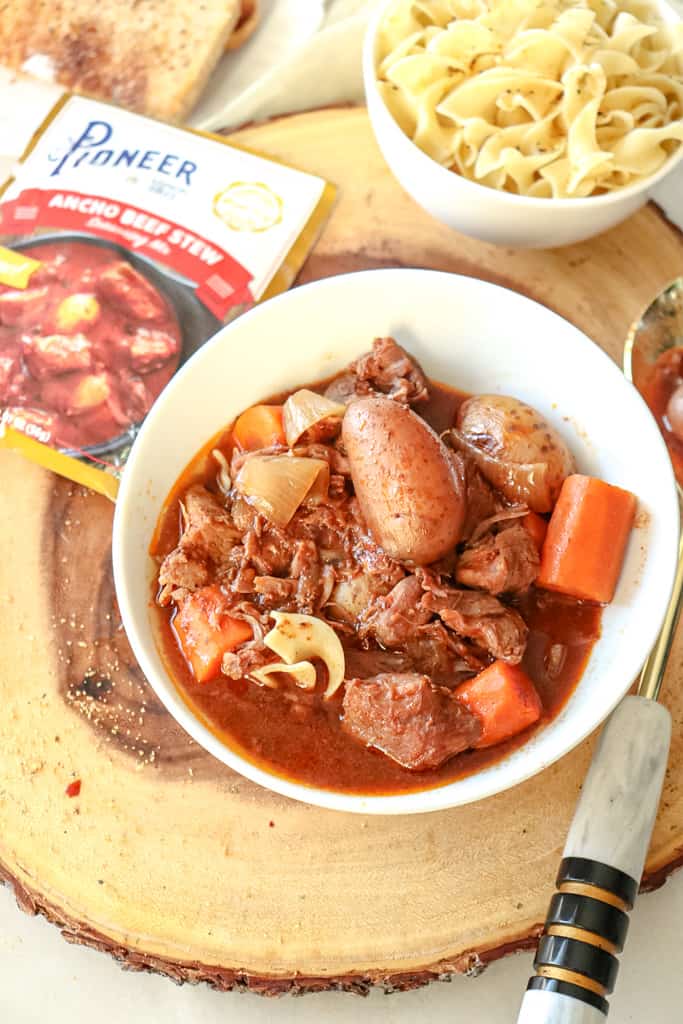 beef stew in a bowl with potatoes and carrots with a serving spoon alongside the bowl