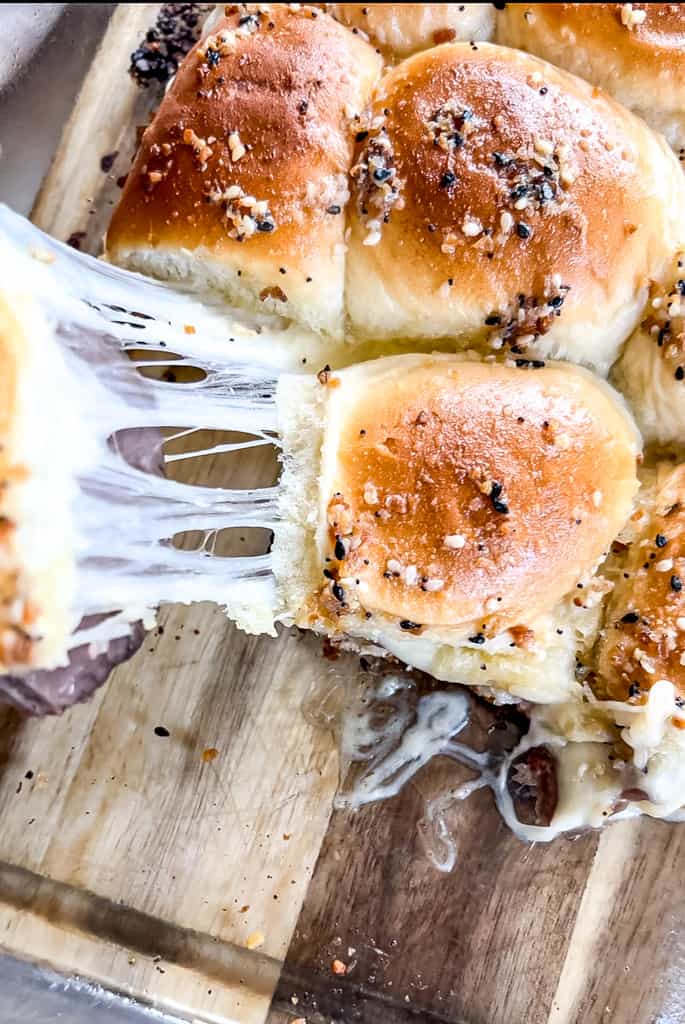 roast beef sliders being pulled apart to reveal melty cheese