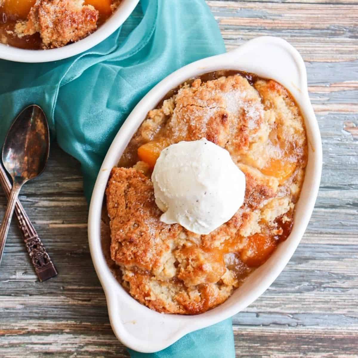 bowl of peach cobbler with a scoop of vanilla ice cream