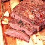 sliced ribeye steak on a cutting board that is cooked medium