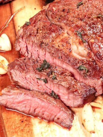 sliced ribeye steak on a cutting board that is cooked medium