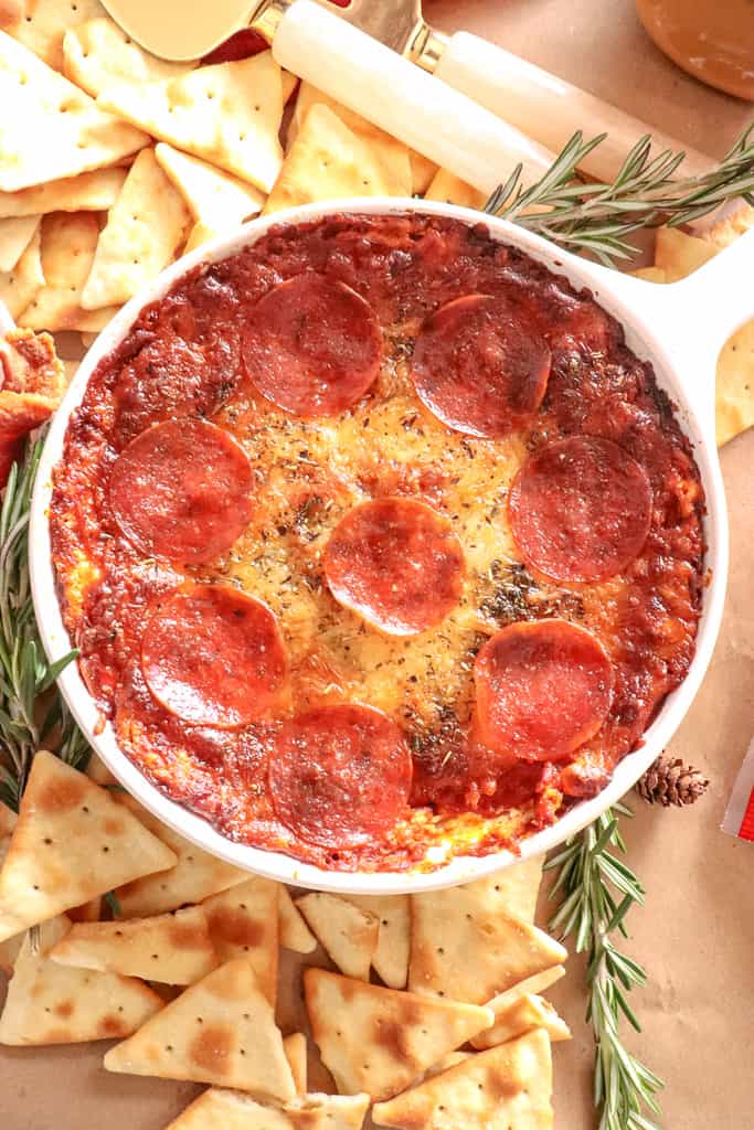 overhead view of a bowl of pizza dip with crackers surrounding it
