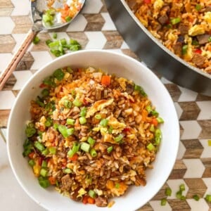 overhead view of beef fried rice in a bowl, next to a skillet with more