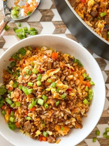 overhead view of beef fried rice in a bowl, next to a skillet with more
