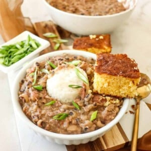 bowl of black eyed peas with a side of cornbread and rice on top