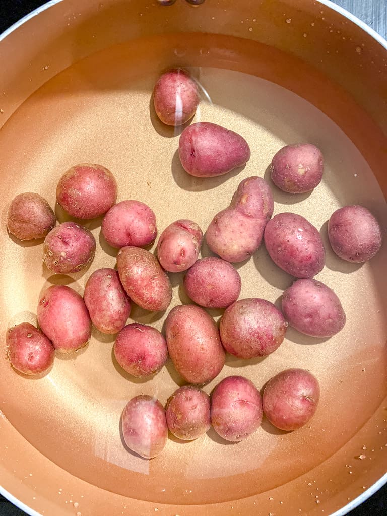 red potatoes submerged in a pot full of water