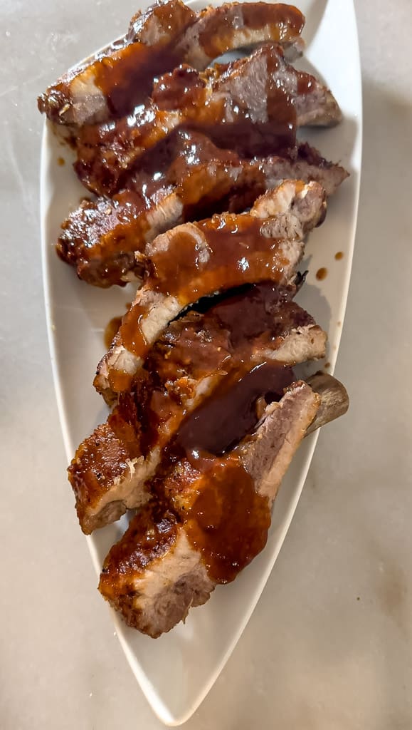 plated baby back ribs drizzled with sauce