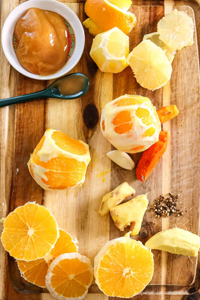 oranges ginger tumeric and garlic laid out on a cutting board