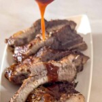 bbq sauce being poured over sliced baby back ribs