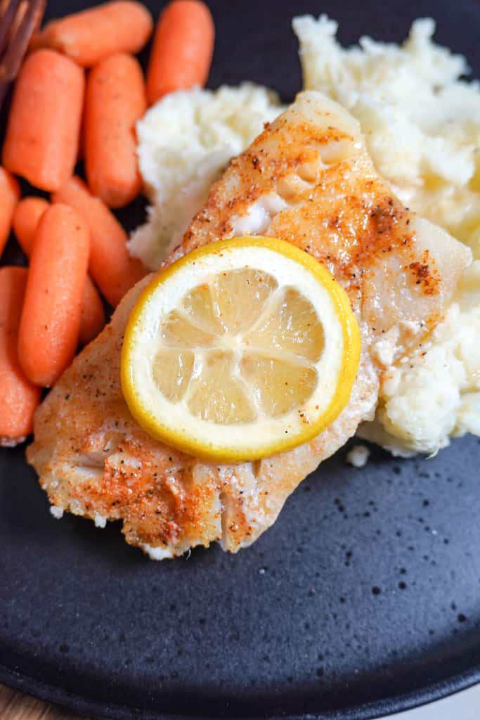 close up view of plated baked cod with mashed potatoes and carrots